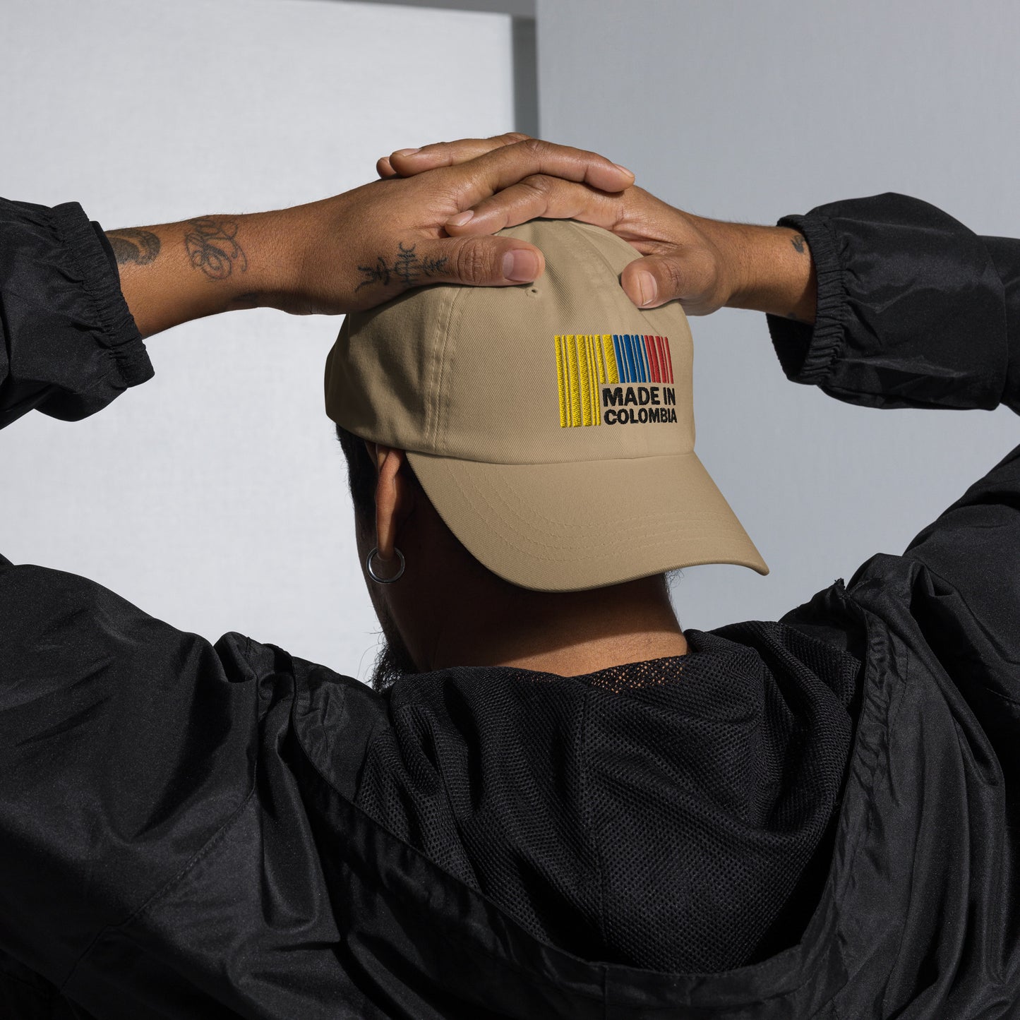 Unisex Stone dad hat featuring a vibrant Colombian-themed design on the side, worn by a model with hands resting on their head, showcasing the hat's stylish look.