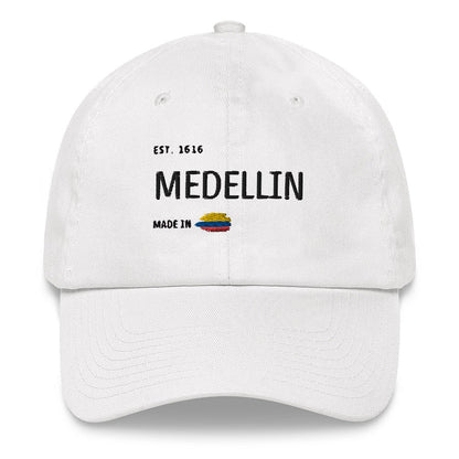 White dad hat featuring 'Medellín - Made in Colombia' embroidery with a small Colombian flag. A stylish and minimal way to represent your city with pride.